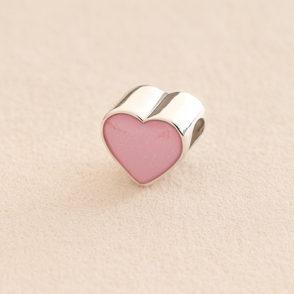 Silver Heart Cremation ashes charm with light pink resin filled with ashes or fur, displayed on a soft beige background – suitable for pet or human memorials.