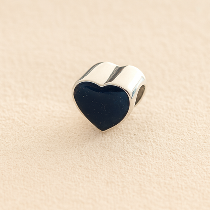 Silver Heart Cremation ashes charm with navy resin filled with ashes or fur, displayed on a soft beige background – suitable for pet or human memorials.