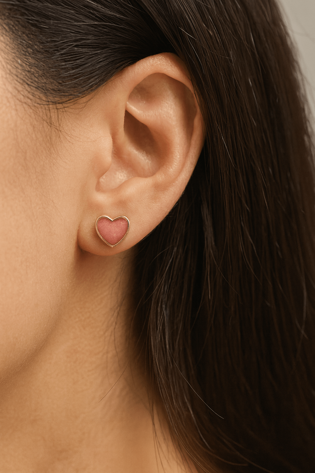Heart-shaped memorial earring worn by a person with dark hair.