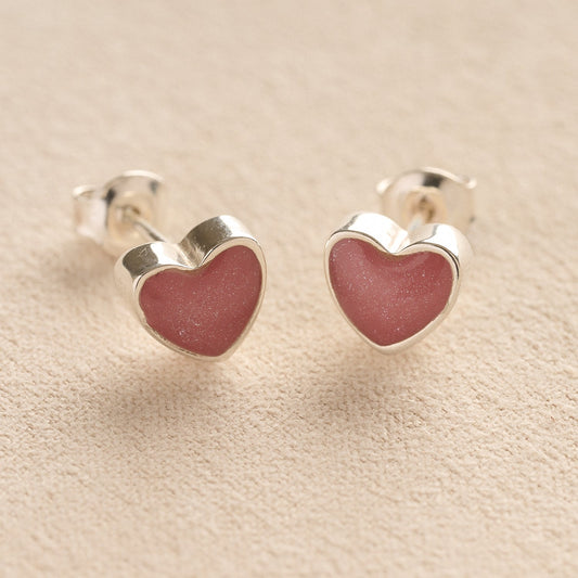 Silver Heart-shaped memorial earrings with dark pink resin with cremation ashes or fur a beige fabric background