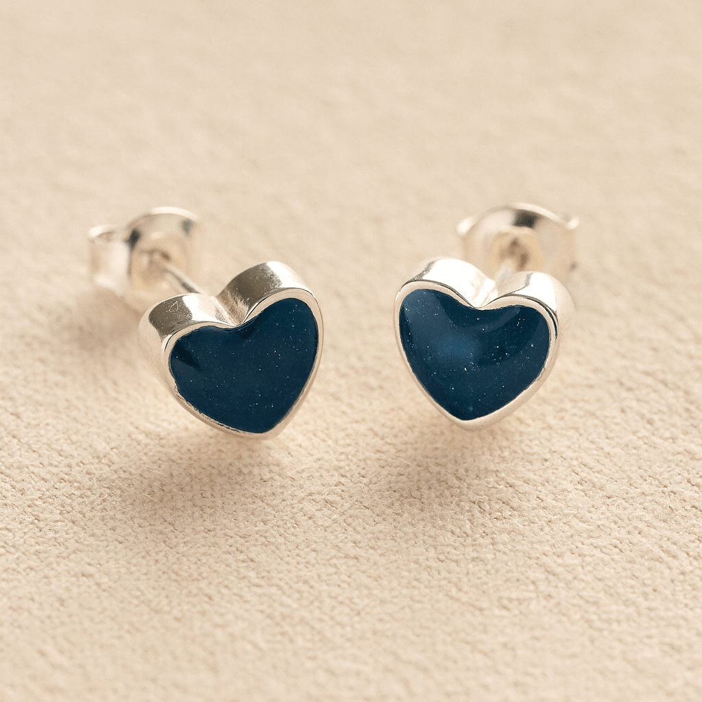 Heart-shaped silver memorial earrings with navy resin with cremation ashes or fur a beige fabric background