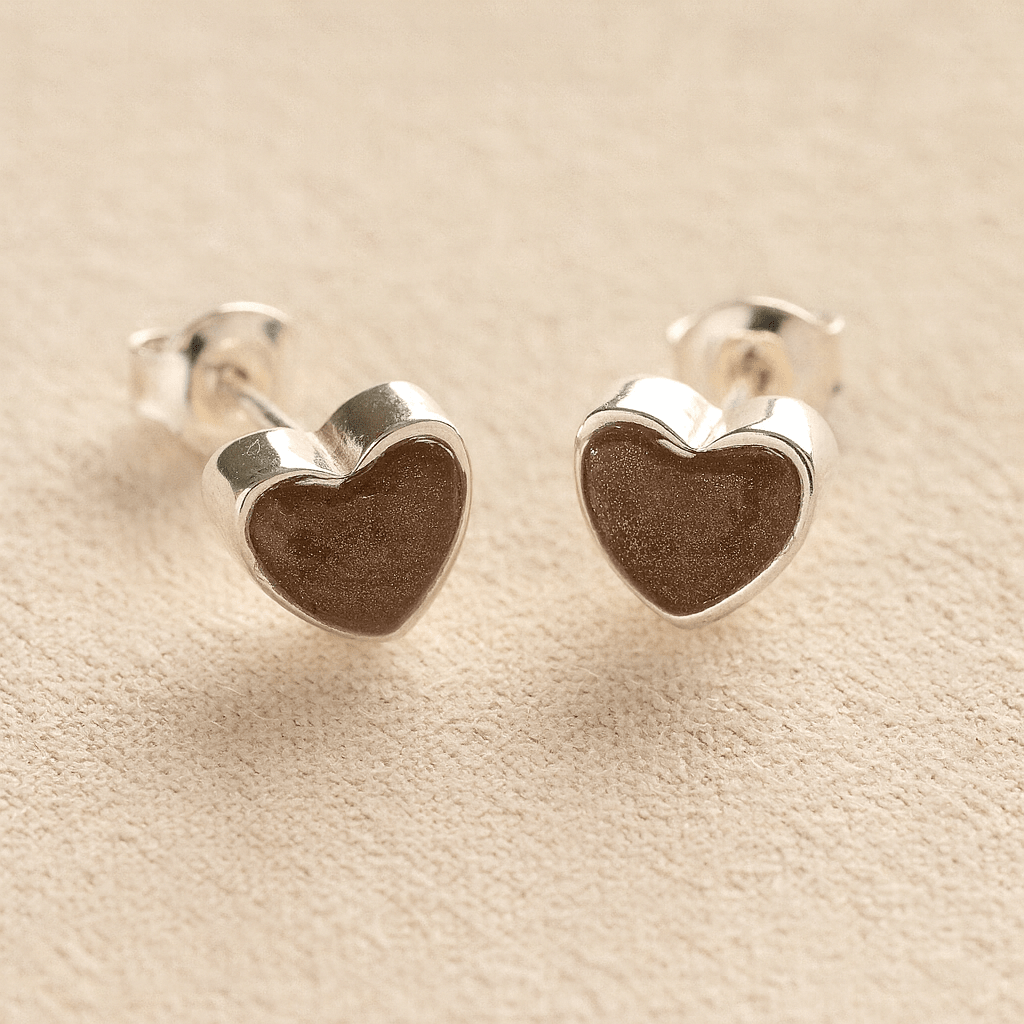 Sterling Silver Heart-shaped ashes earrings with mocha resin with cremation ashes or fur a beige fabric background