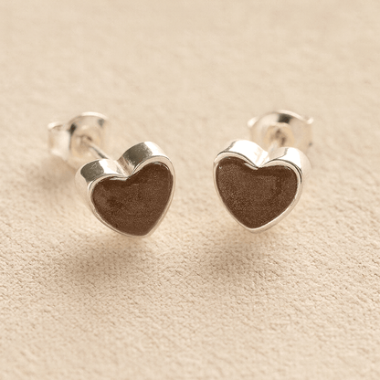 Sterling Silver Heart-shaped ashes earrings with mocha resin with cremation ashes or fur a beige fabric background