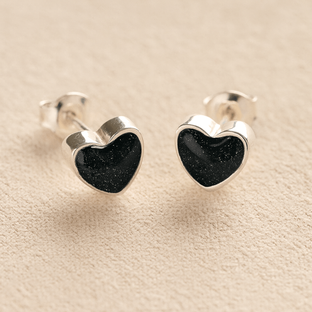 Sterling Silver Heart-shaped cremation earrings with black resin with cremation ashes or fur a beige fabric background