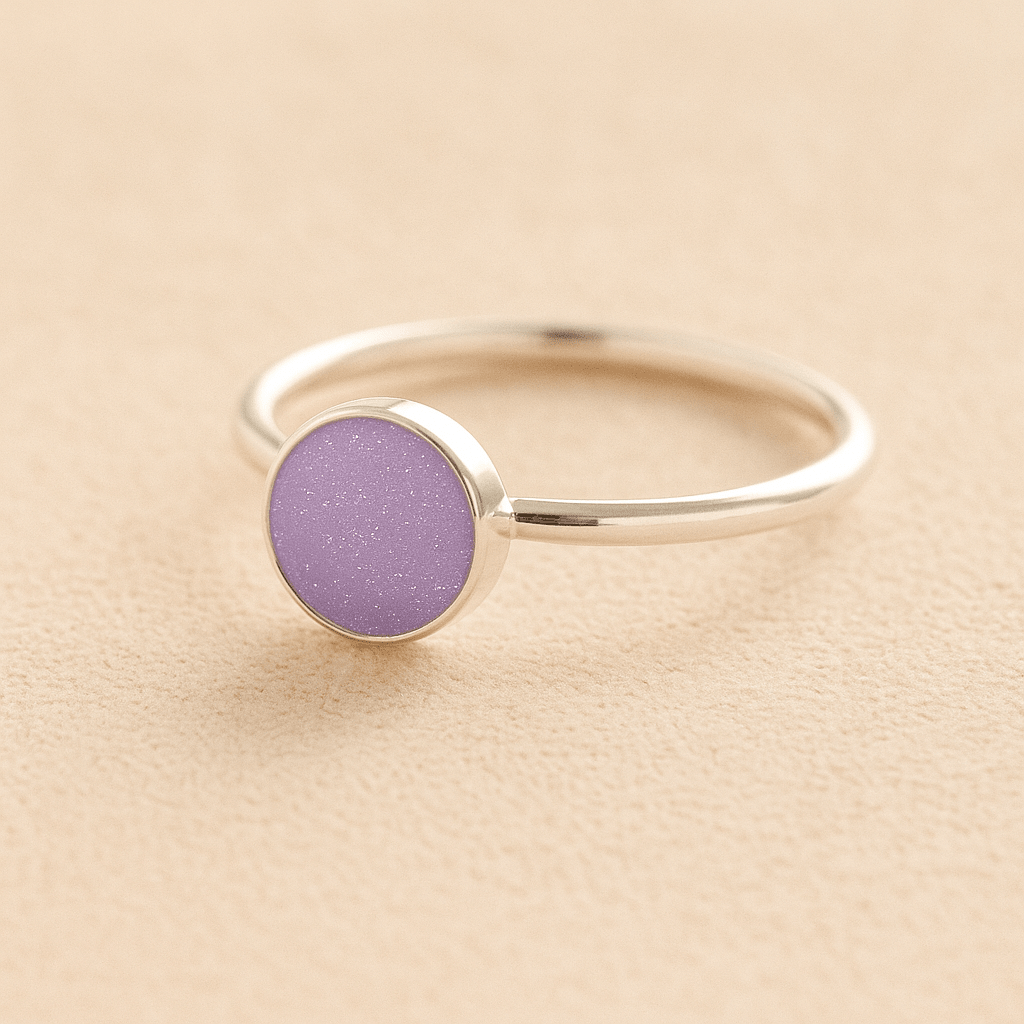 Silver memorial ashes ring with a lavender resin circle bezel on a beige background