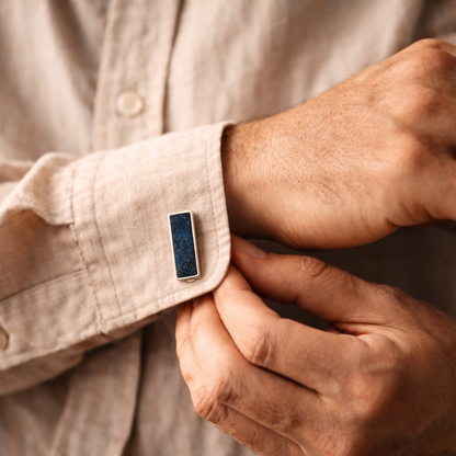 Man adjusting an ashes cufflink on a beige shirt sleeve.