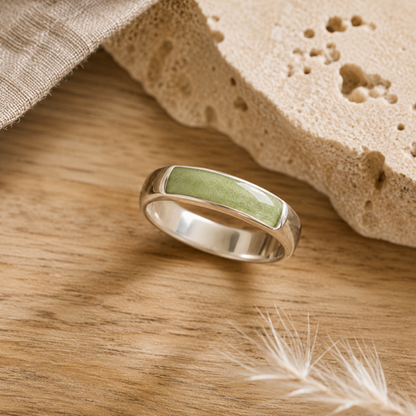 Silver mens ashes ring with sage resin inset for ashes, fur and hair on a wooden surface with a stone and feather.