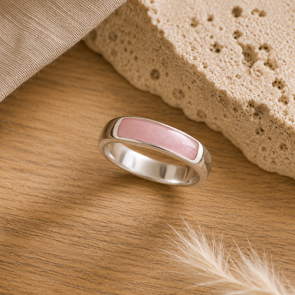 Silver mens ashes ring with blush resin inset for ashes, fur and hair on a wooden surface with a stone and feather.