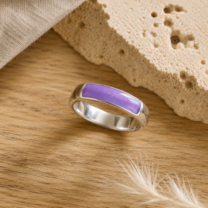 Silver mens ashes ring with lavender resin inset for ashes, fur and hair on a wooden surface with a stone and feather.