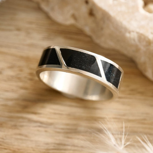 Mens Silver ashes ring with black inlay on a wooden surface