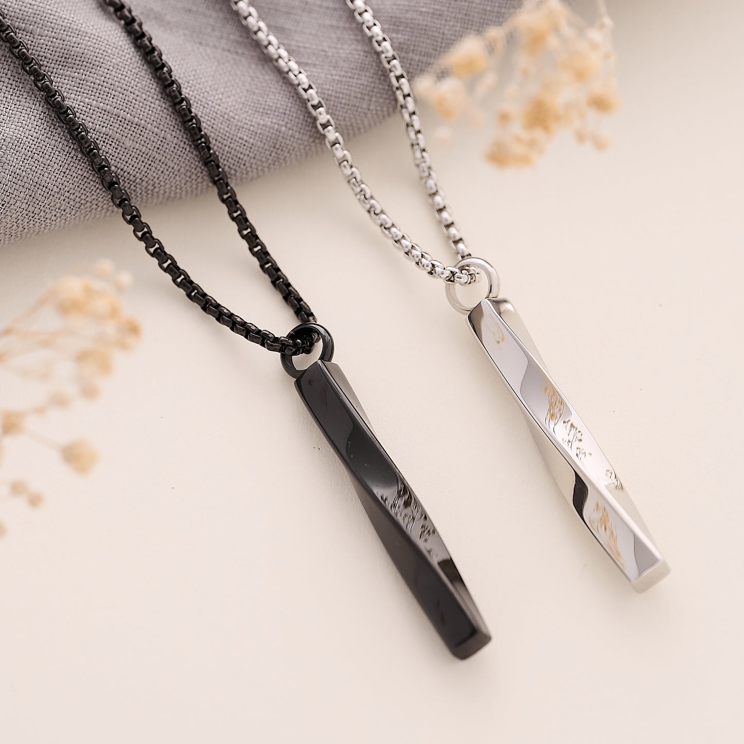 Two mens memorial necklaces on a light background