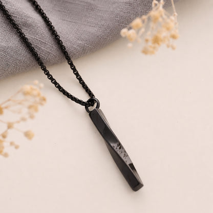 Black twist cremation necklace on a light surface with dried flowers