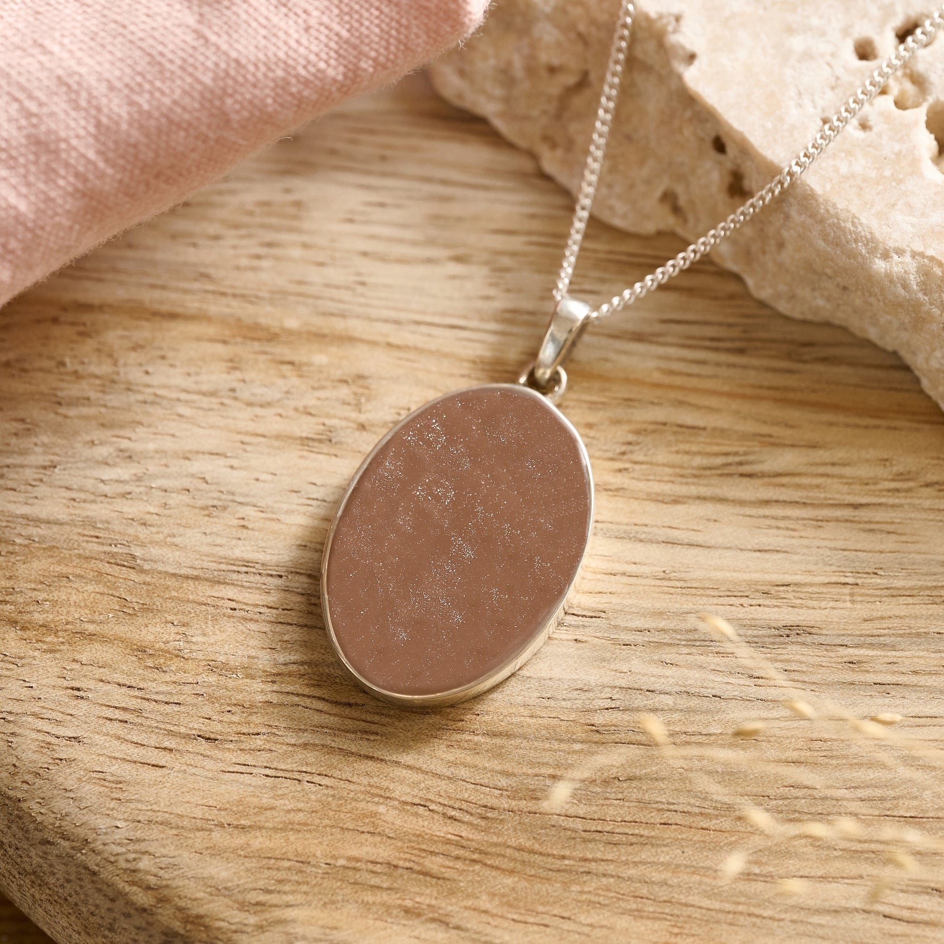 Sterling silver oval cremation necklace with mocha resin in natural light