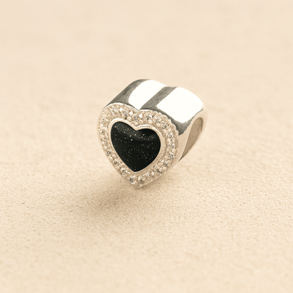 heart-shaped ashes charm with a black resin infill on a beige background 