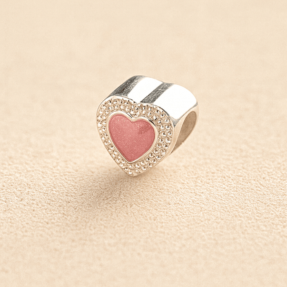 Silver Heart-shaped cremation charm with pink resin center and crystal border on beige background
