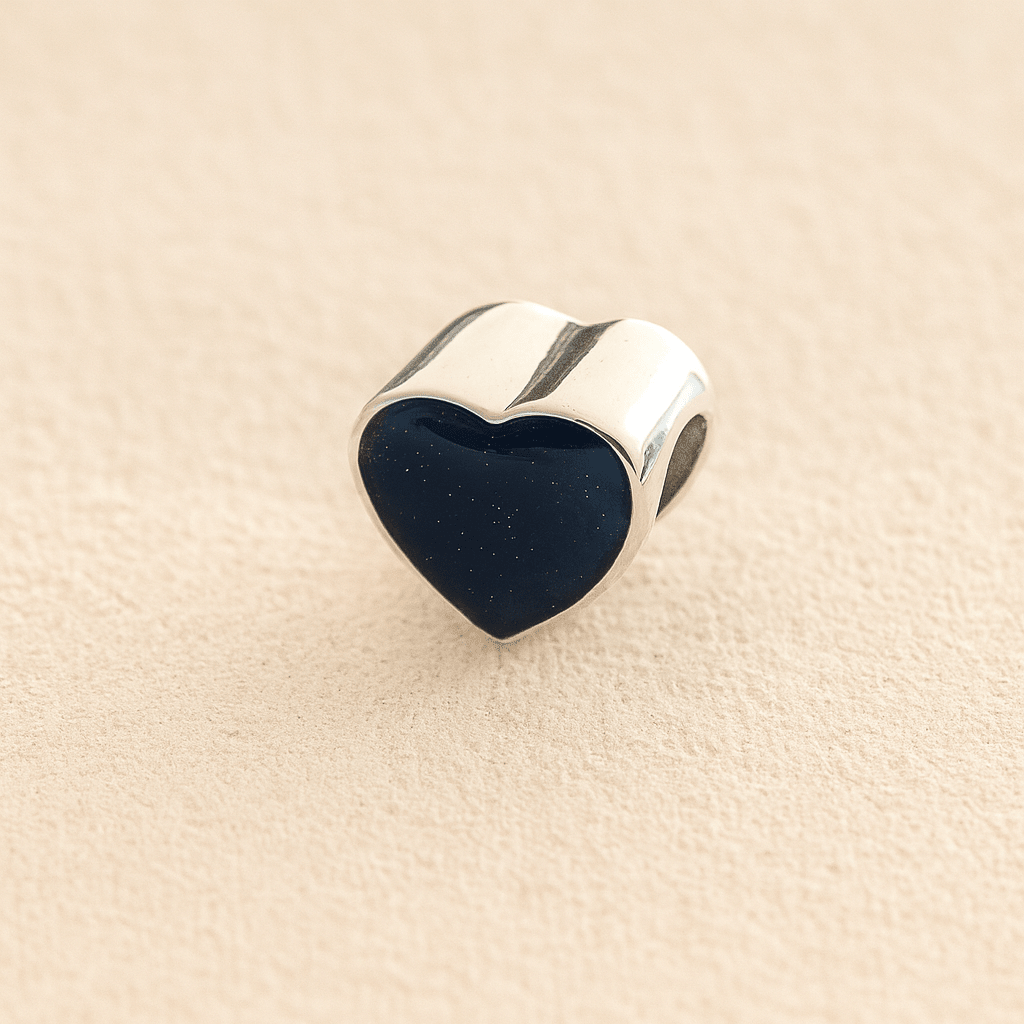 Silver Heart Cremation ashes charm with navy resin filled with ashes or fur, displayed on a soft beige background – suitable for pet or human memorials.