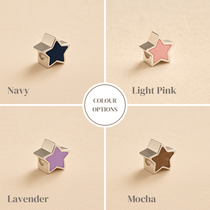 Star-shaped ashes charms in navy, light pink, lavender, and mocha colors on a beige background.