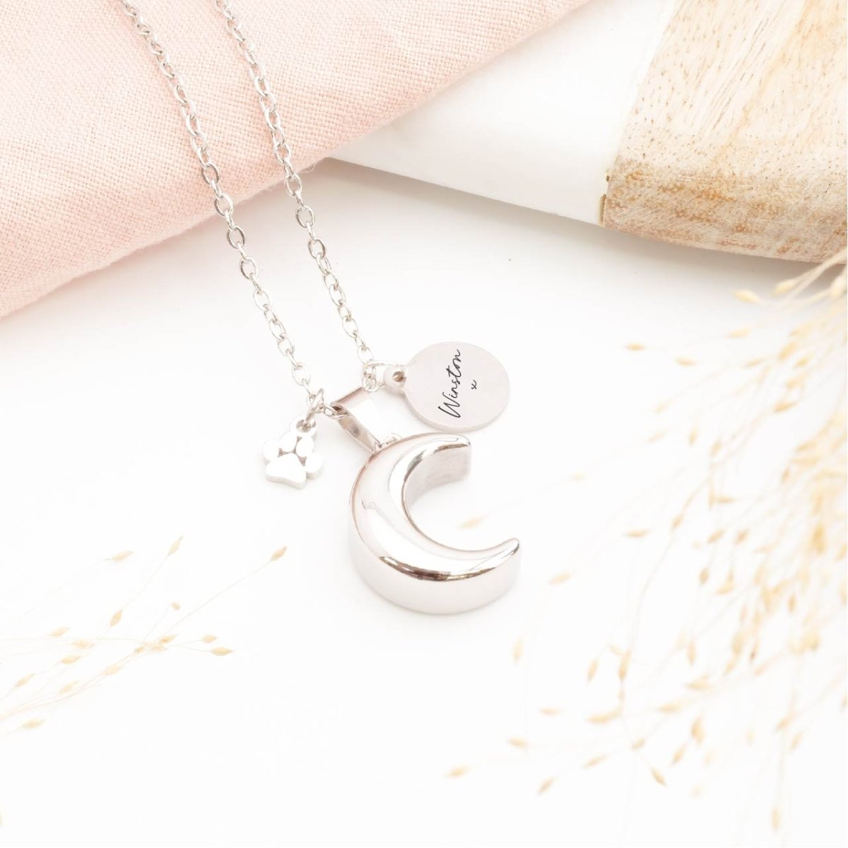 Silver pet memorial necklace in a moon shape, engraved tag and paw print charm 