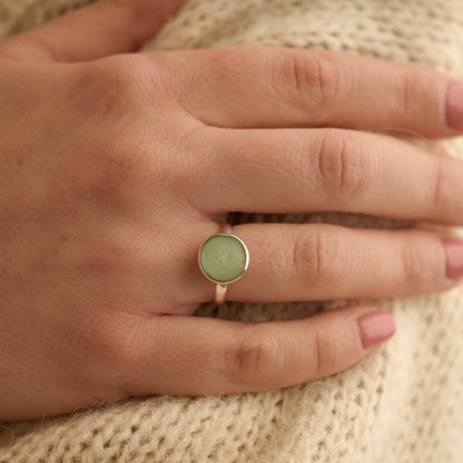 Sterling silver round cremation ashes ring in sage resin worn by woman holding her arm