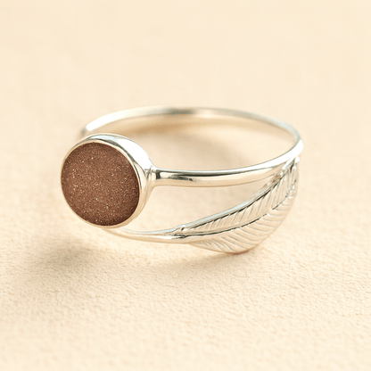 Adjustable Silver feather ashes ring with a mocha resin on a beige background
