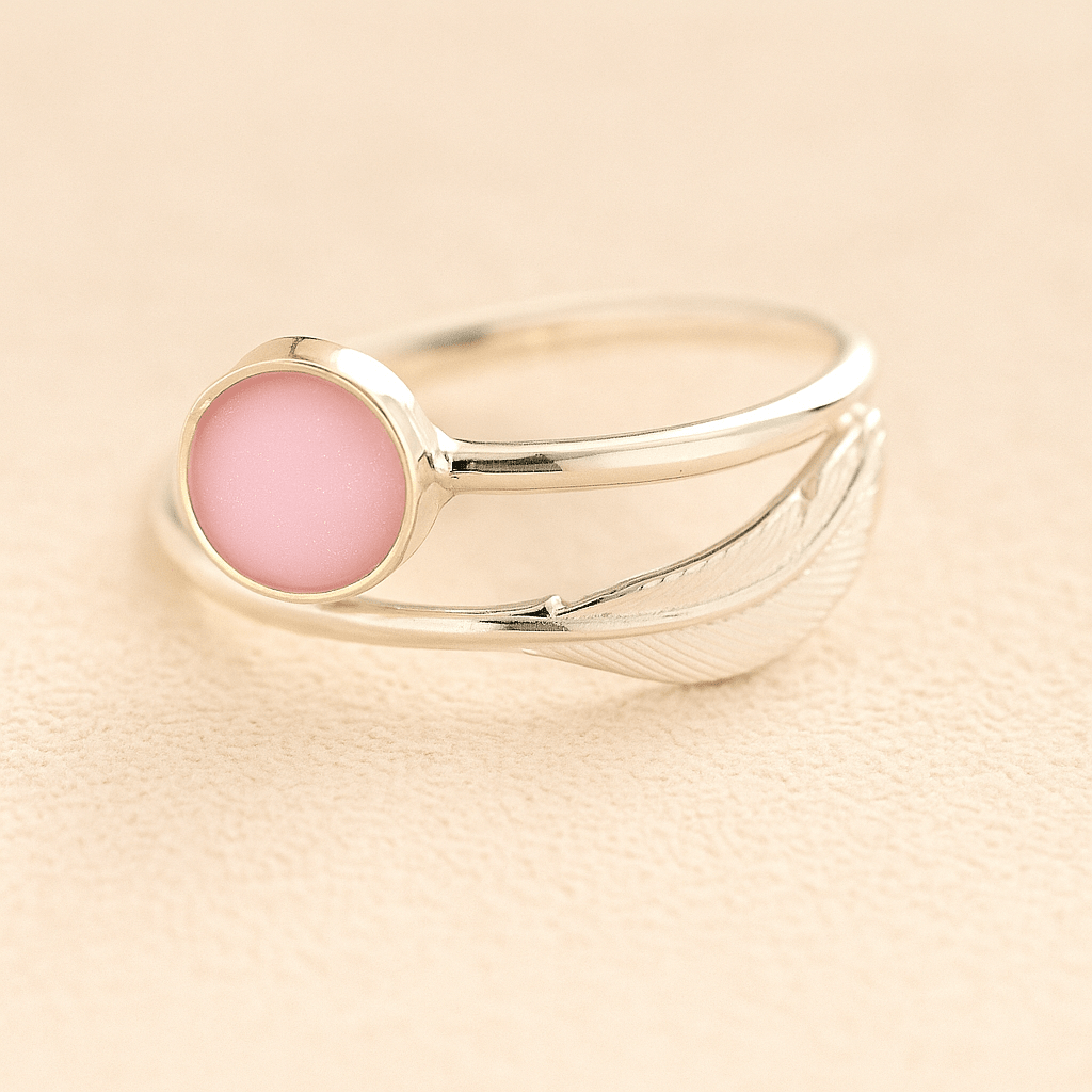 Sterling Silver adjustable feather ashes ring with light pink resin on a beige background