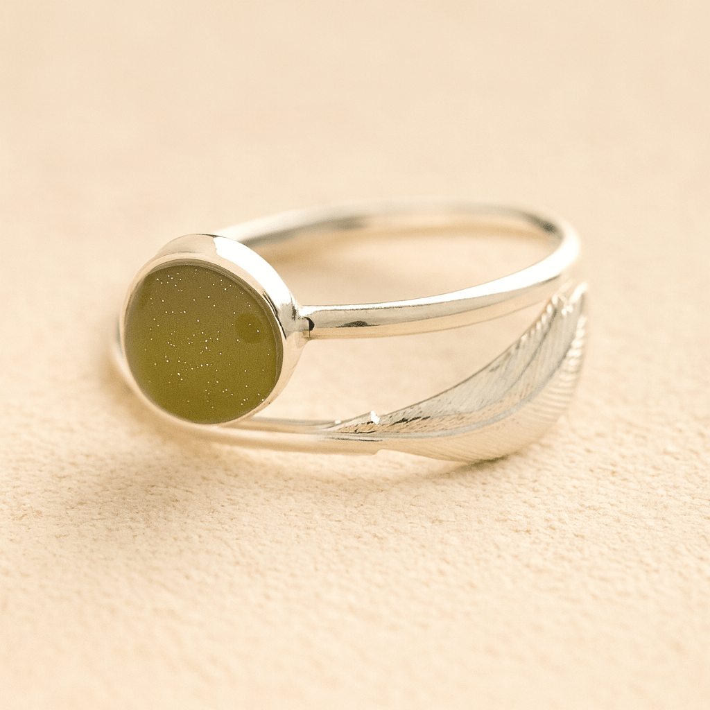 Silver adjustable feather ashes ring with a sage resin on a beige background