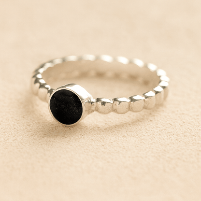 Silver bubble cremation ring with black resin on a beige background.