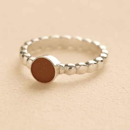 Silver bubble cremation ring with mocha resin on a beige background.