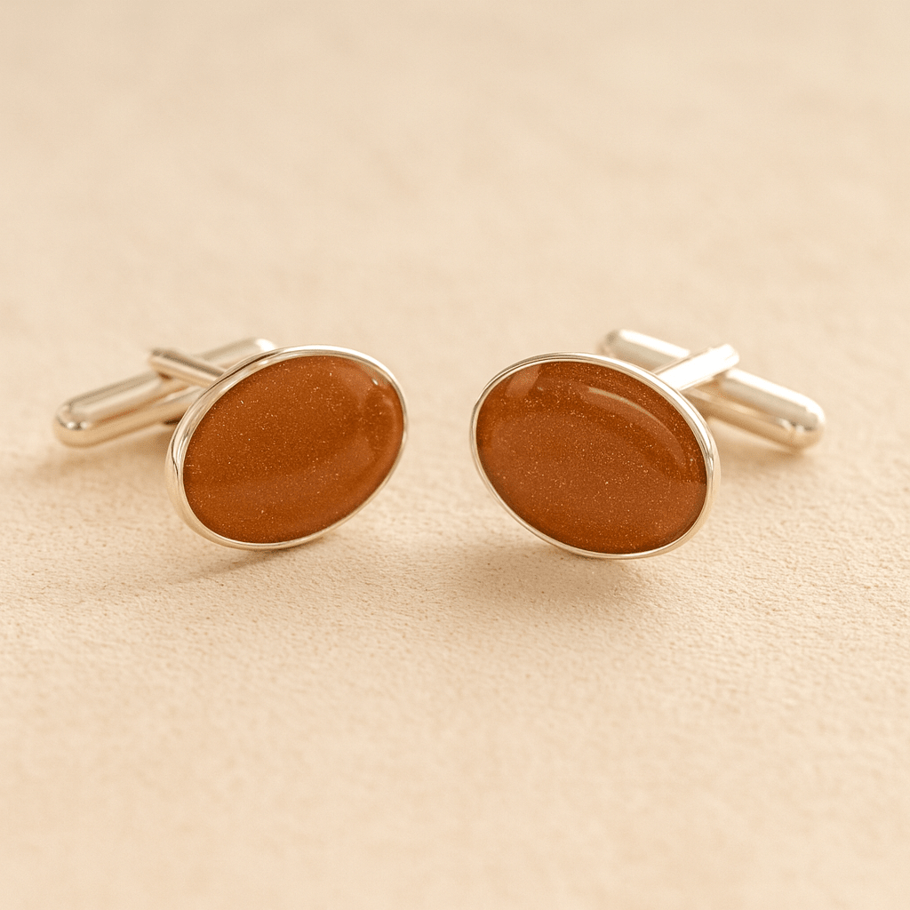 Silver oval ashes cufflinks with a rust resin infill made with ashes or fur on a beige background