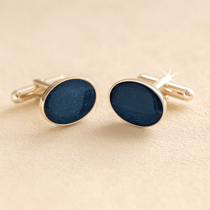 Silver oval ashes cufflinks with a navy resin infill made with ashes or fur on a beige background