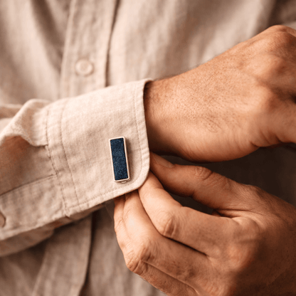 Man adjusting an ashes cufflink on a beige shirt sleeve.