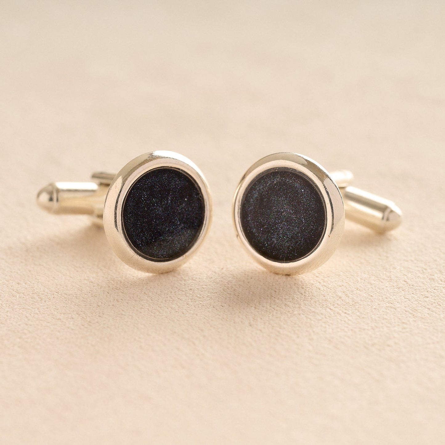 Silver Memorial Ashes Cufflinks with black resin with ashes or fur on a beige background