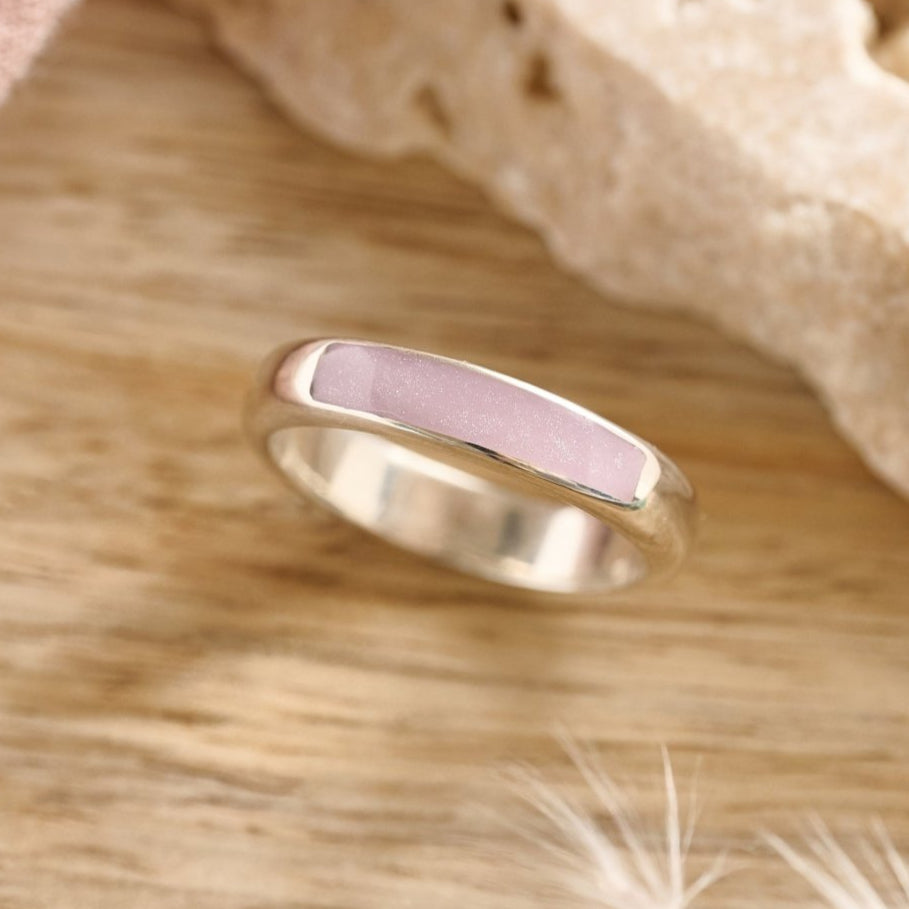 Sterling silver cremation ashes ring with lavender resin on a wooden table