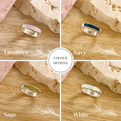 Four silver cremation rings in different colors (Lavender, Navy, Sage, White) on a wooden surface with a neutral background.