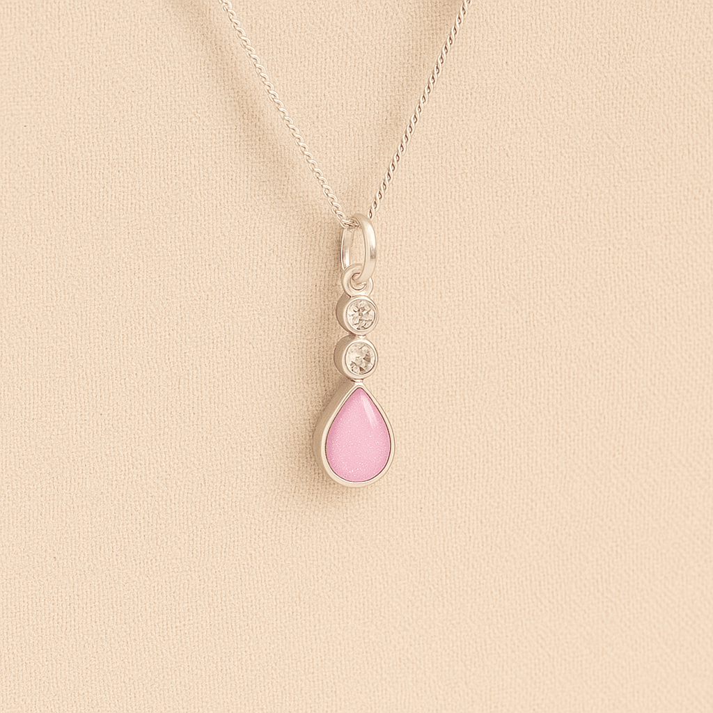 Silver Cremation ashes necklace with a teardrop pendant and light pink resin filled with ashes or fur, displayed on a soft beige background – suitable for pet or human memorials.