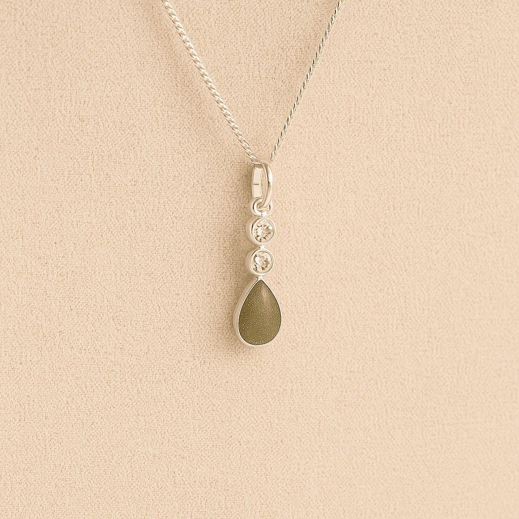 Silver Cremation ashes necklace with a teardrop pendant and sage resin filled with ashes or fur, displayed on a soft beige background – suitable for pet or human memorials.