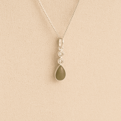 Silver Cremation ashes necklace with a teardrop pendant and sage resin filled with ashes or fur, displayed on a soft beige background – suitable for pet or human memorials.