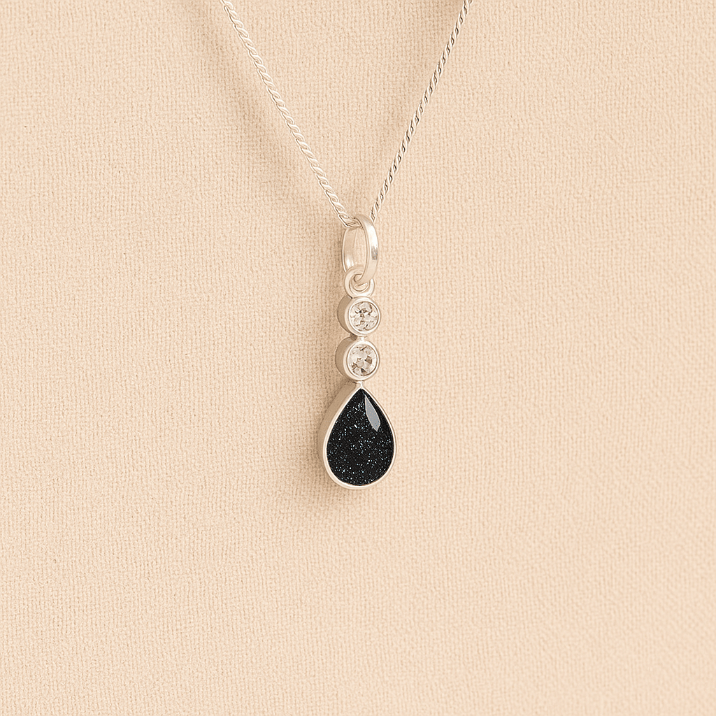 Silver Cremation ashes necklace with a teardrop pendant and black resin filled with ashes or fur, displayed on a soft beige background – suitable for pet or human memorials.