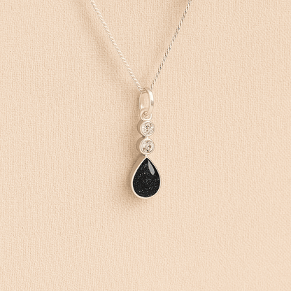 Silver Cremation ashes necklace with a teardrop pendant and black resin filled with ashes or fur, displayed on a soft beige background – suitable for pet or human memorials.