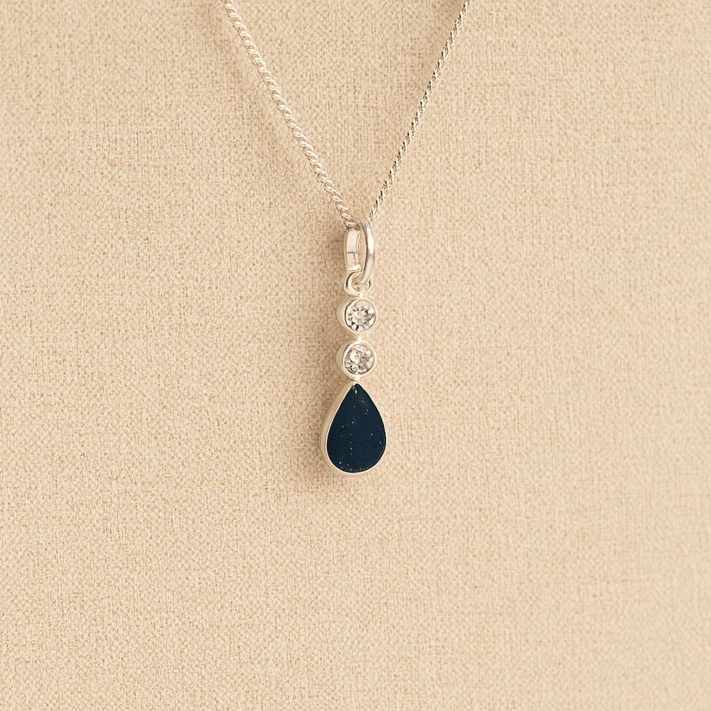 Silver Cremation ashes necklace with a teardrop pendant and navy resin filled with ashes or fur, displayed on a soft beige background – suitable for pet or human memorials.