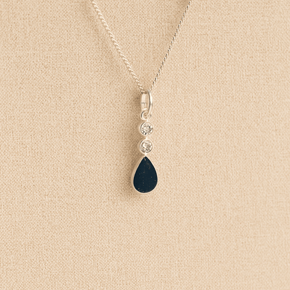 Silver Cremation ashes necklace with a teardrop pendant and navy resin filled with ashes or fur, displayed on a soft beige background – suitable for pet or human memorials.