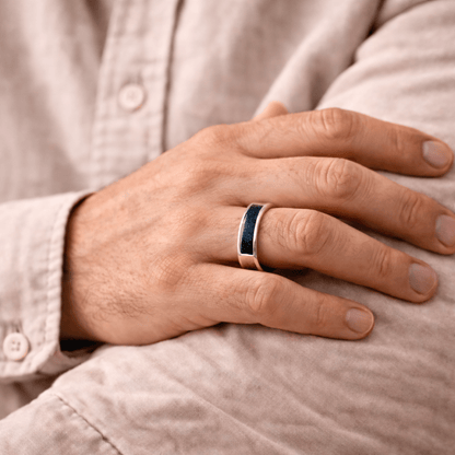 A man wearing an ashes ring with navy resin infill for ashes, hair or fur