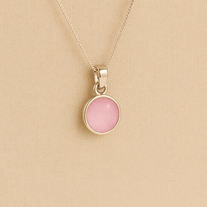 A round Silver Cremation ashes necklace light pink resin filled with ashes or fur, displayed on a soft beige background – suitable for pet or human memorials.