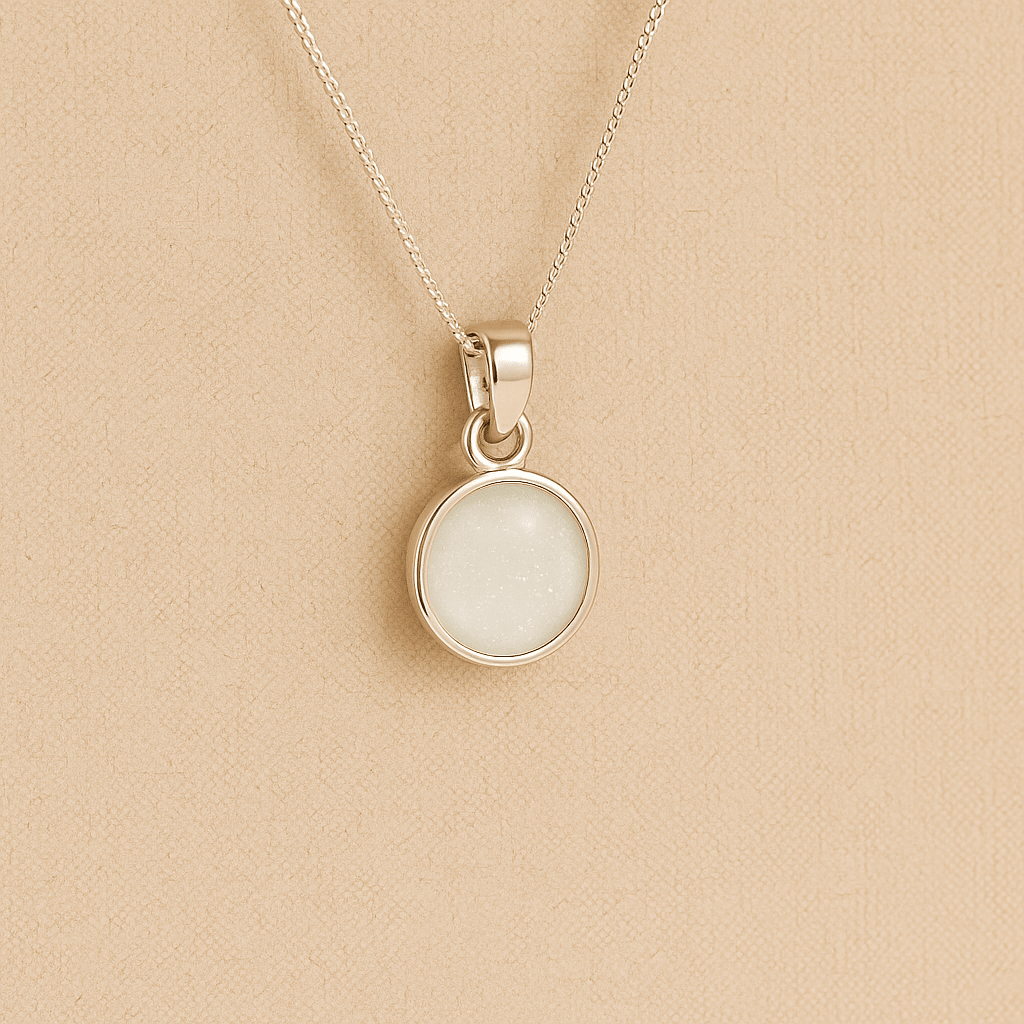 Silver Cremation ashes necklace with a round pendant and white resin filled with ashes or fur, displayed on a soft beige background – suitable for pet or human memorials.