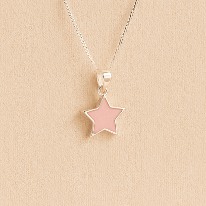 Silver star memorial pendant with light pink resin on a beige background