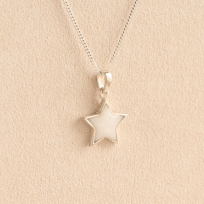 Silver star memorial pendant with white resin on a beige background