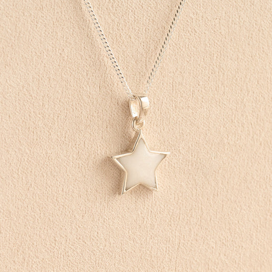Silver star memorial pendant with white resin on a beige background