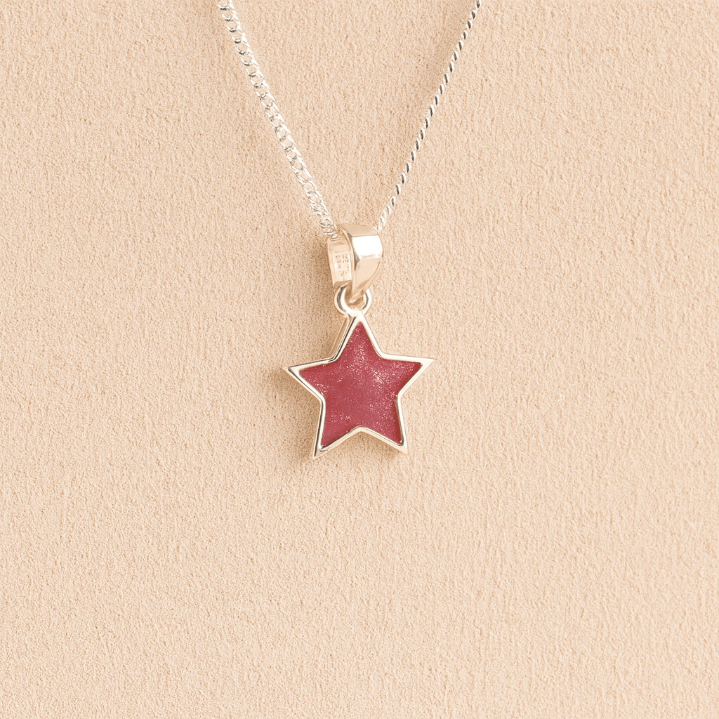 Silver star ashes necklace with dark pink resin on a beige background
