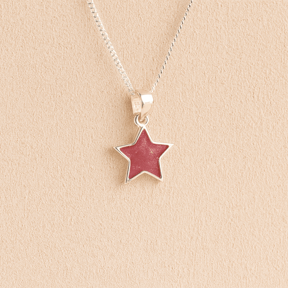 Silver star ashes necklace with dark pink resin on a beige background