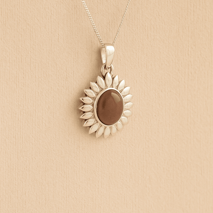 Silver Sunflower Memorial Necklace with a mocha resin infill containing ashes or fur set on a beige textured background